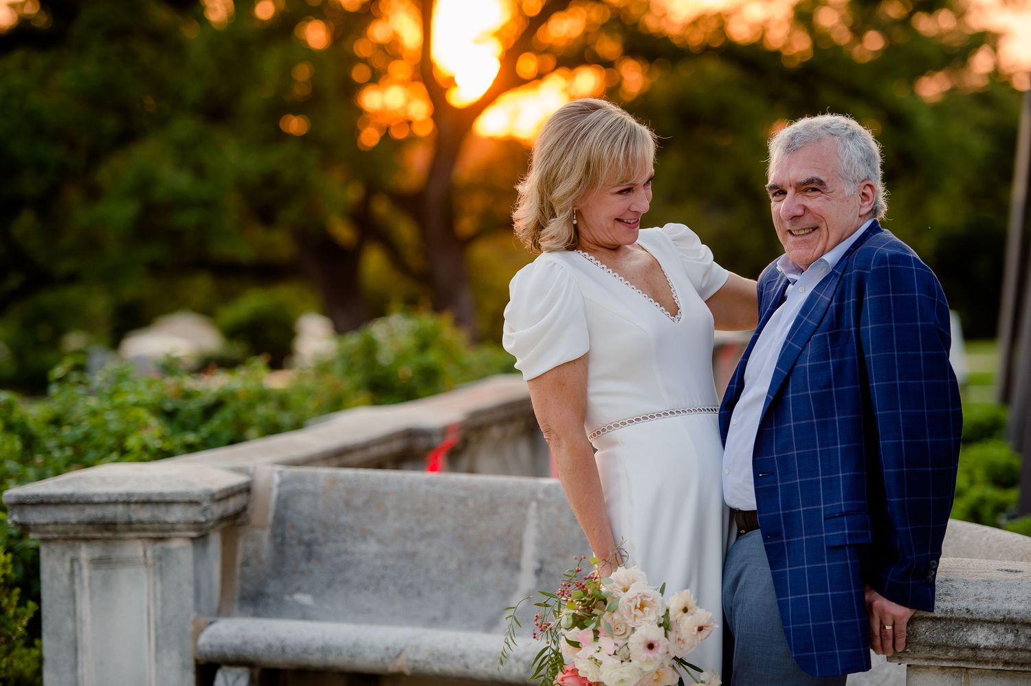 Romantic sunset moment captured at an outdoor venue with floral bouquet.