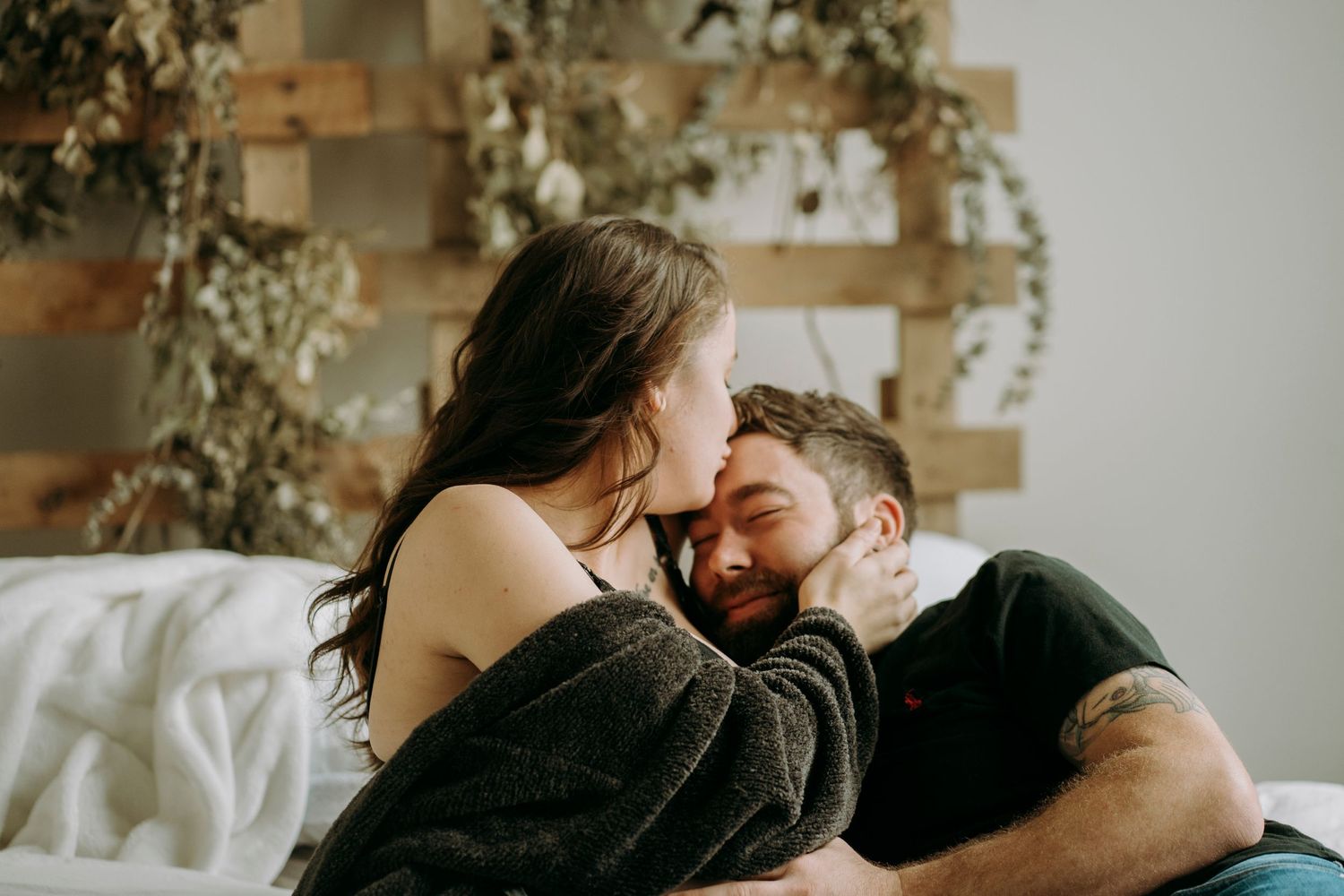 Intimate moment shared between couple on bed with decorative backdrop.