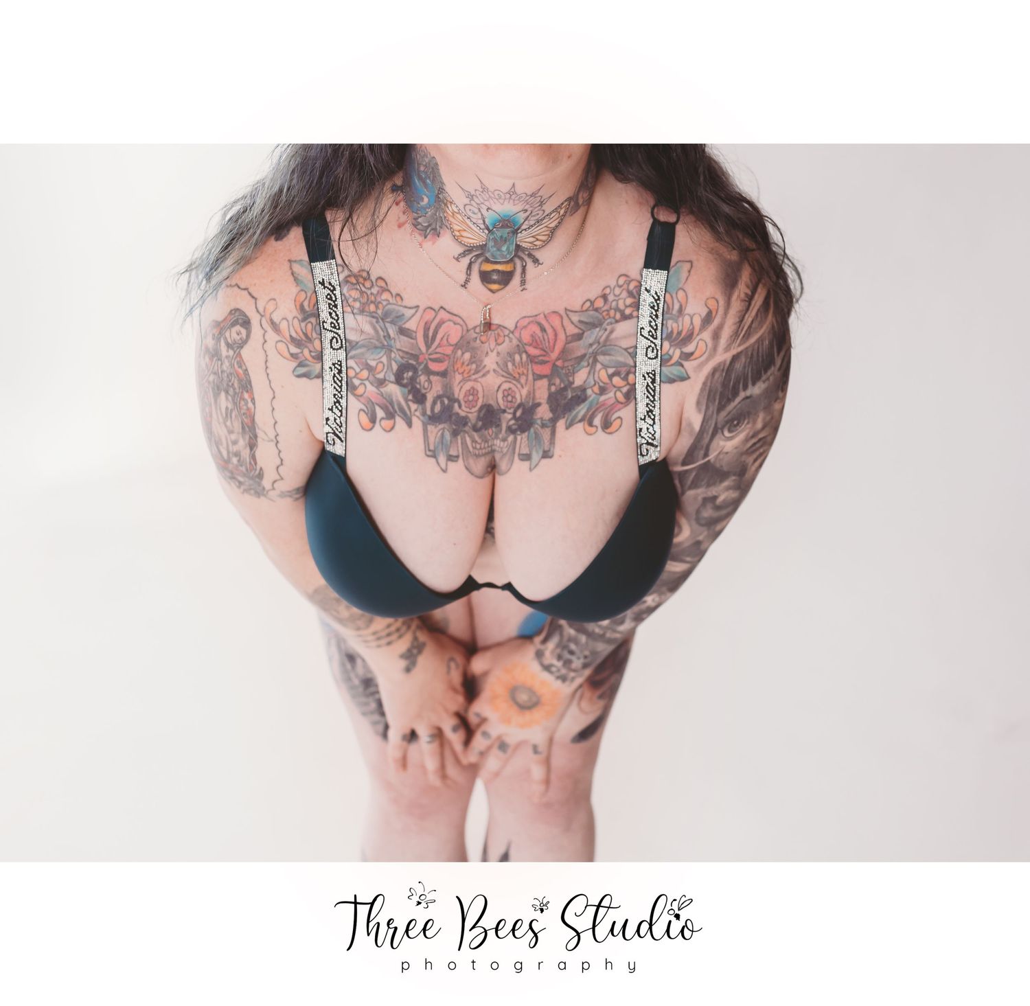 Close-up of torso with intricate tattoo art and black lingerie.