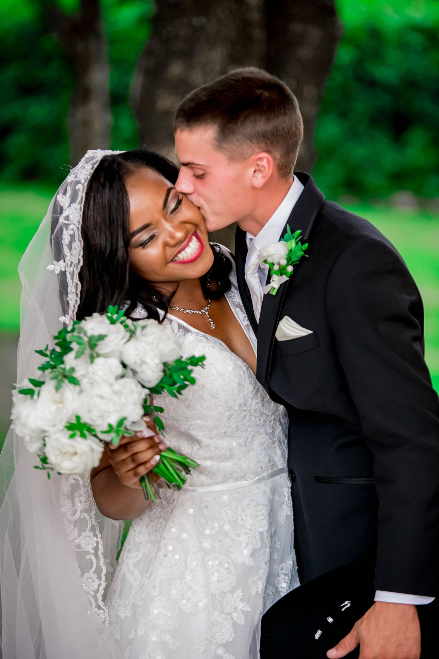 Sweet outdoor wedding moment with white and green floral bouquet.