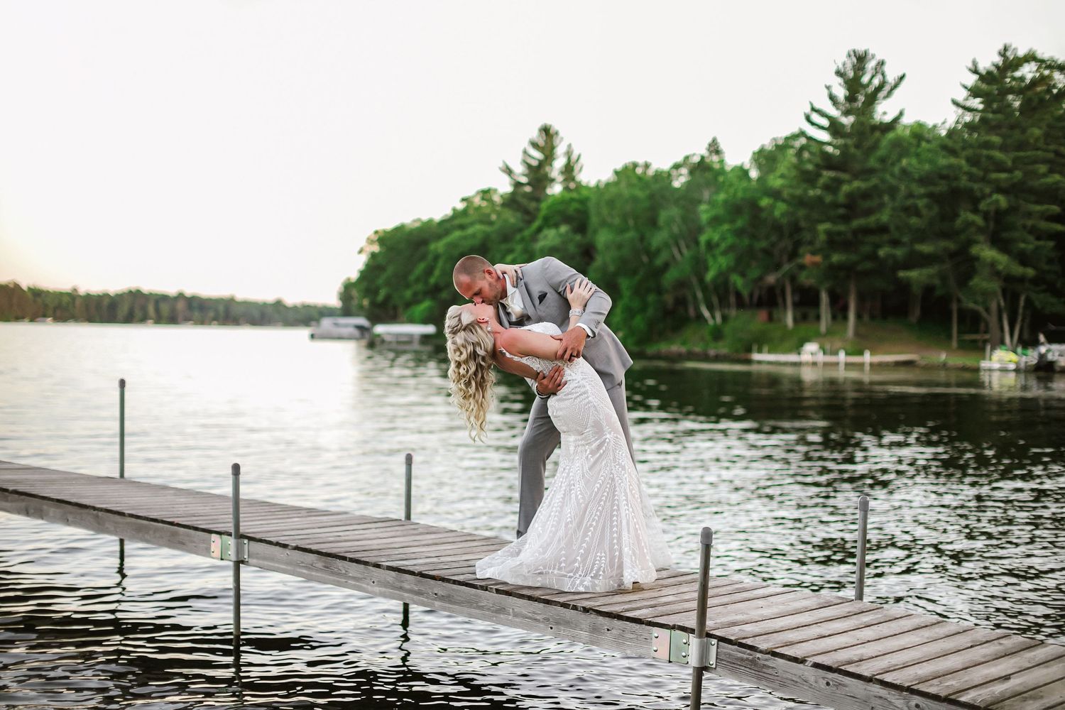 Bride and groom kissing on dock during Minnesota lakeshore wedding, photography by Laura Leigh Images