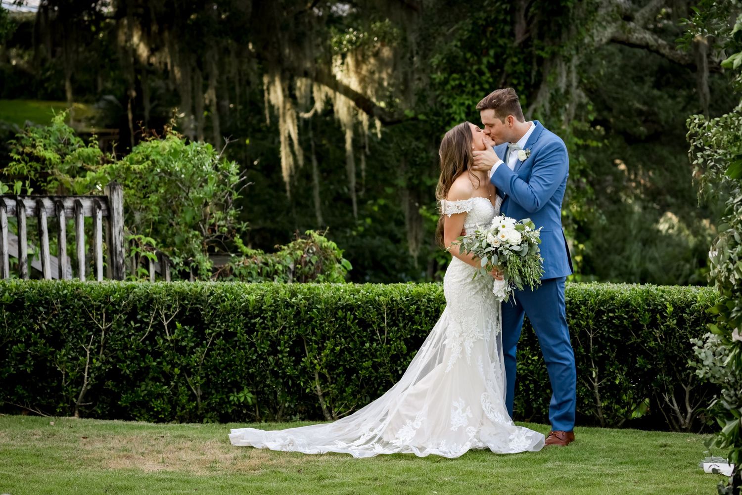 A romantic garden wedding portrait with Spanish moss and white picket fence in the background.