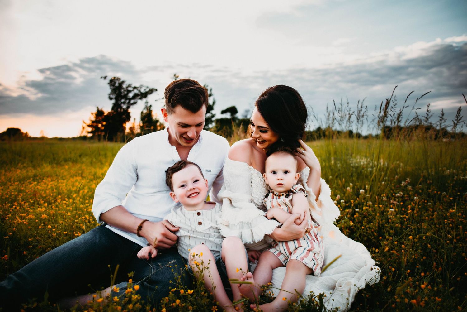 Family relaxing together in blooming wildflower field during spring.