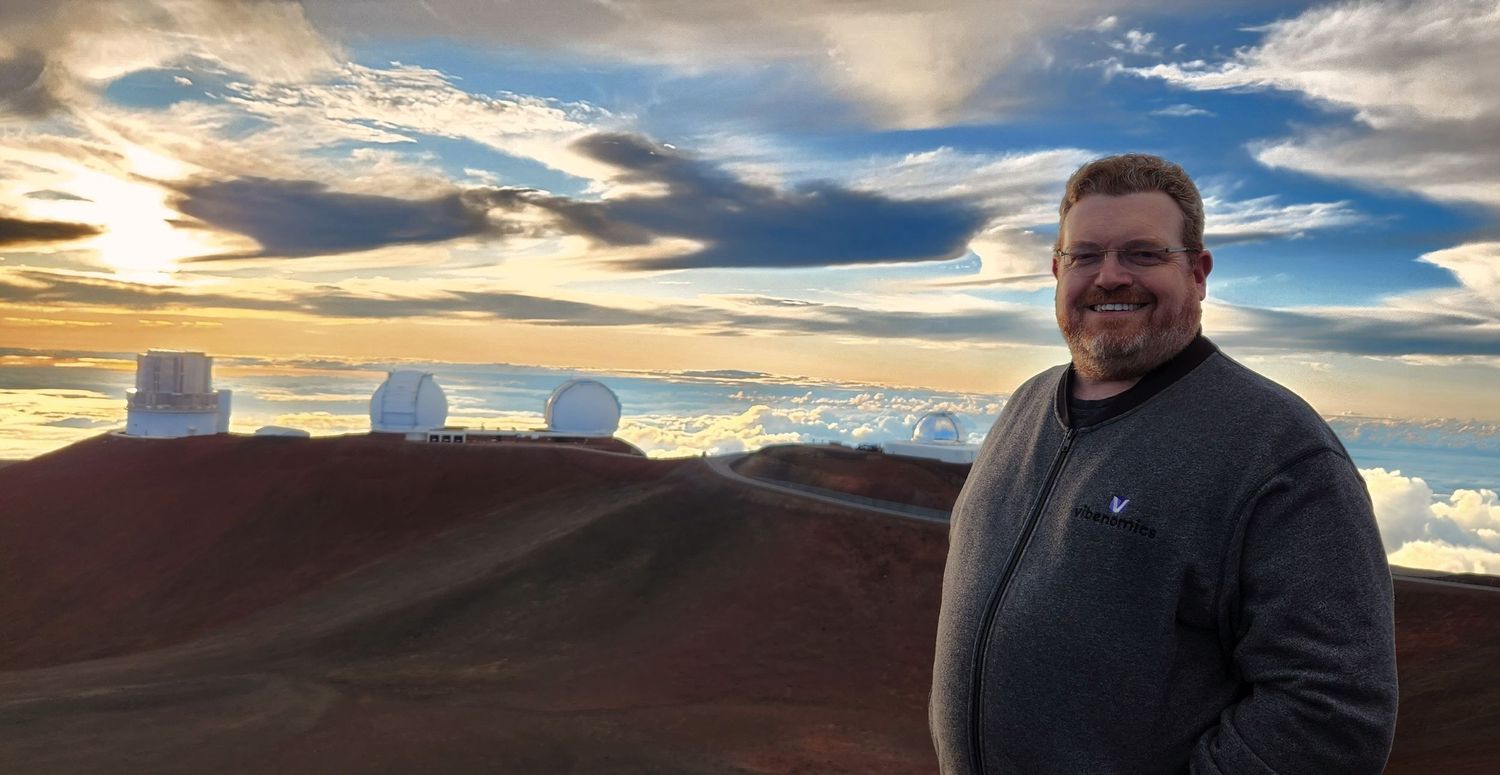 Dave standing at the top of Mauna Kea with the Subaru and Keck telescopes in the background. Photo credit: Esther Fanche