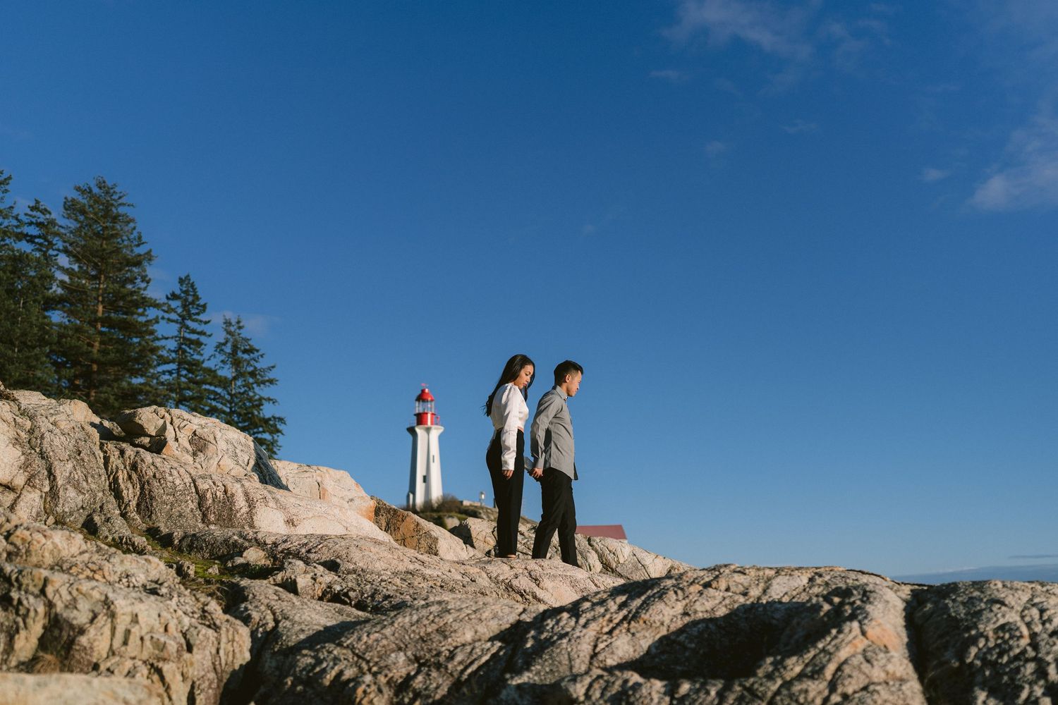 Group posing on rocky coastal cliffs against bright blue sky.