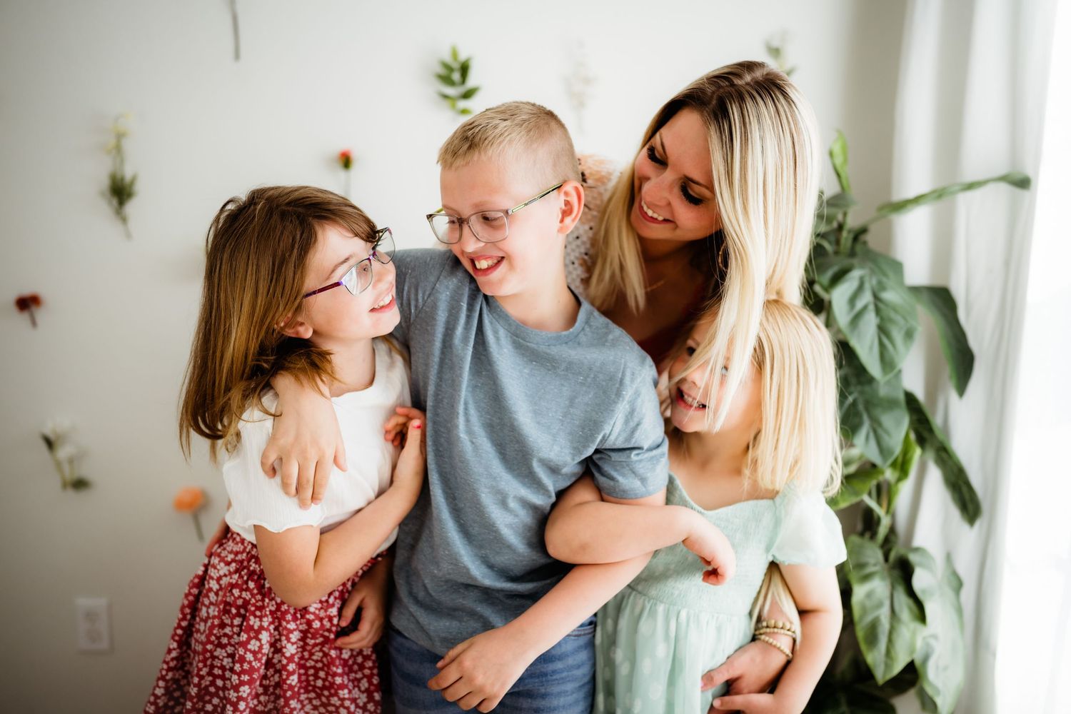 Family portrait with children against white wall decorated with botanical elements.
