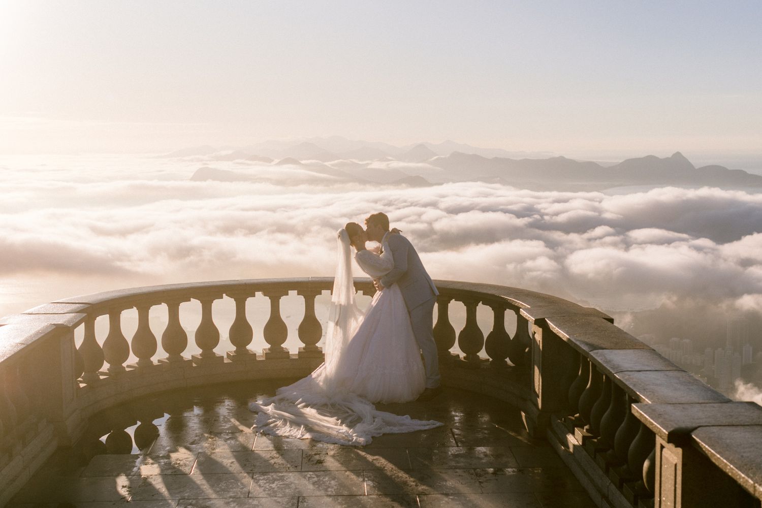 A romantic moment on a balcony overlooking a sea of clouds at sunset.