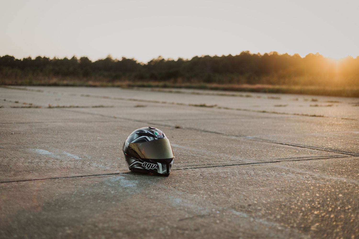 A lone motorcycle helmet sits on dry ground during golden hour sunset.