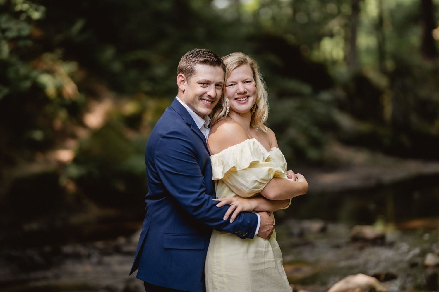 A smiling engaged couple dressed in a blue suit and yellow