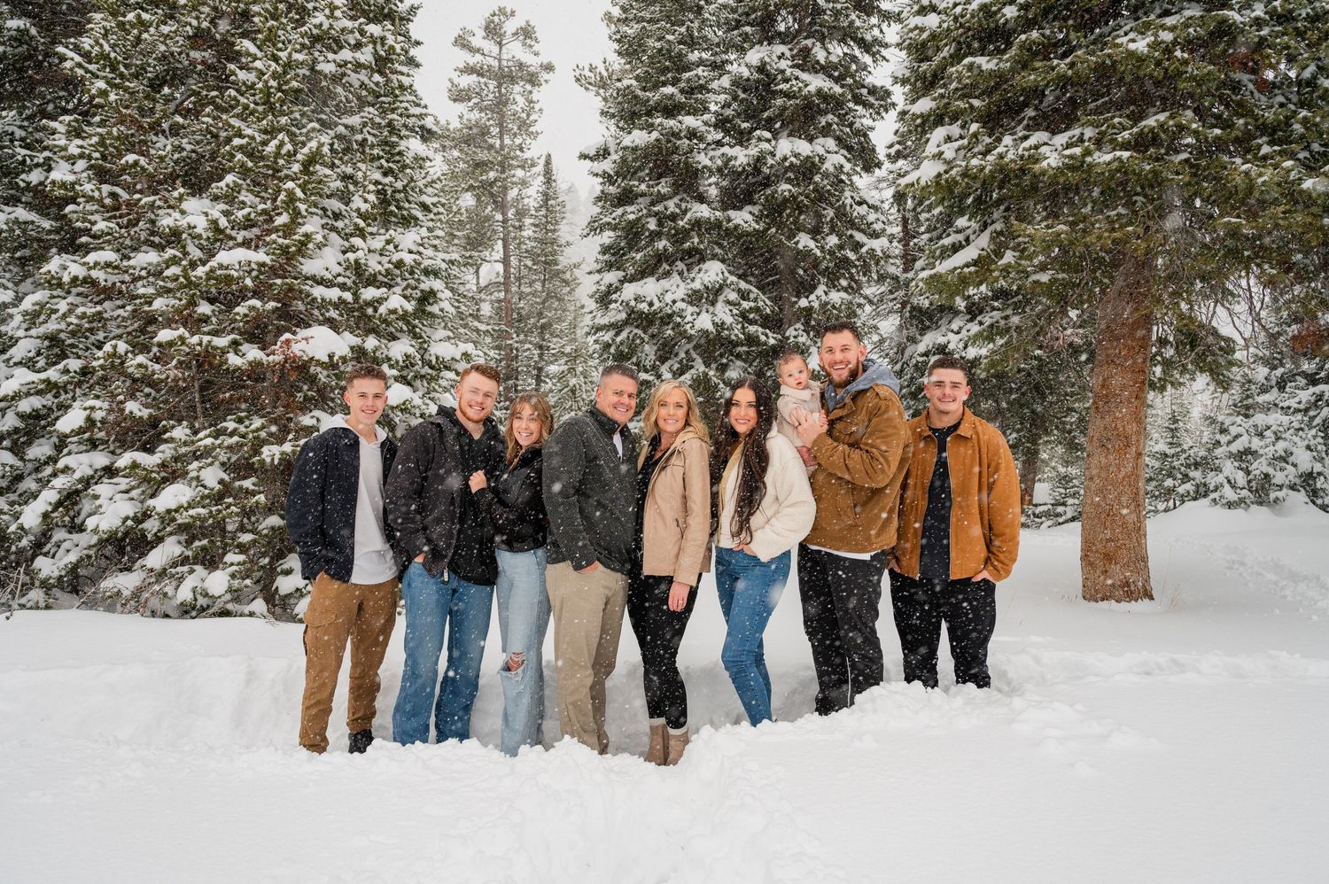 Group photo of friends standing together in a snowy winter forest landscape.