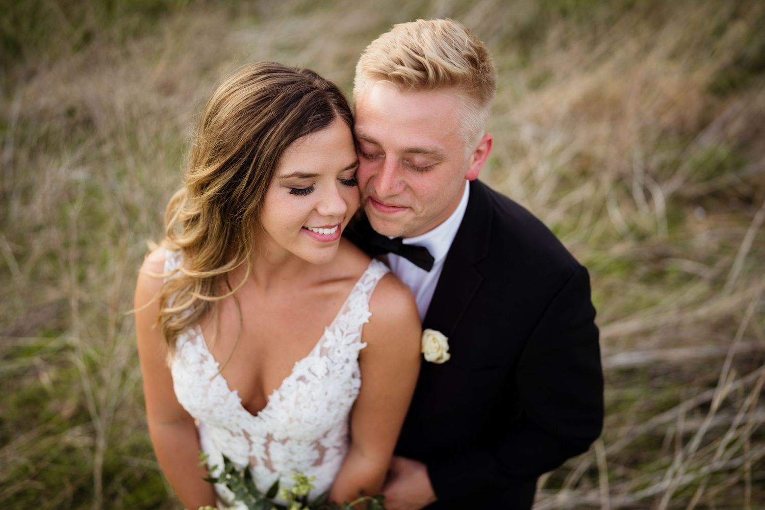 A romantic wedding portrait of a couple in a rustic field.