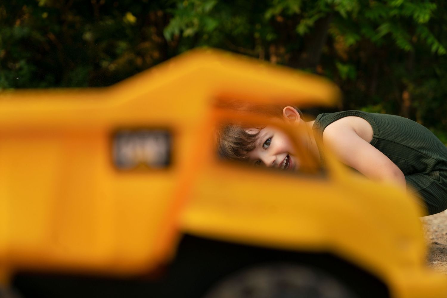 young boy smiles through window of toy dump truck