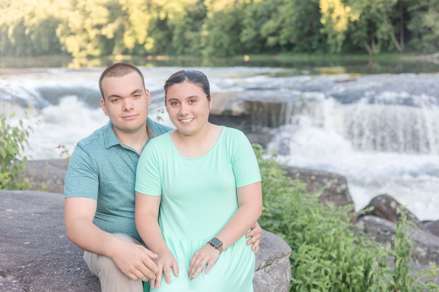 Engagement photos captured near a scenic waterfall with couple in mint green outfits.