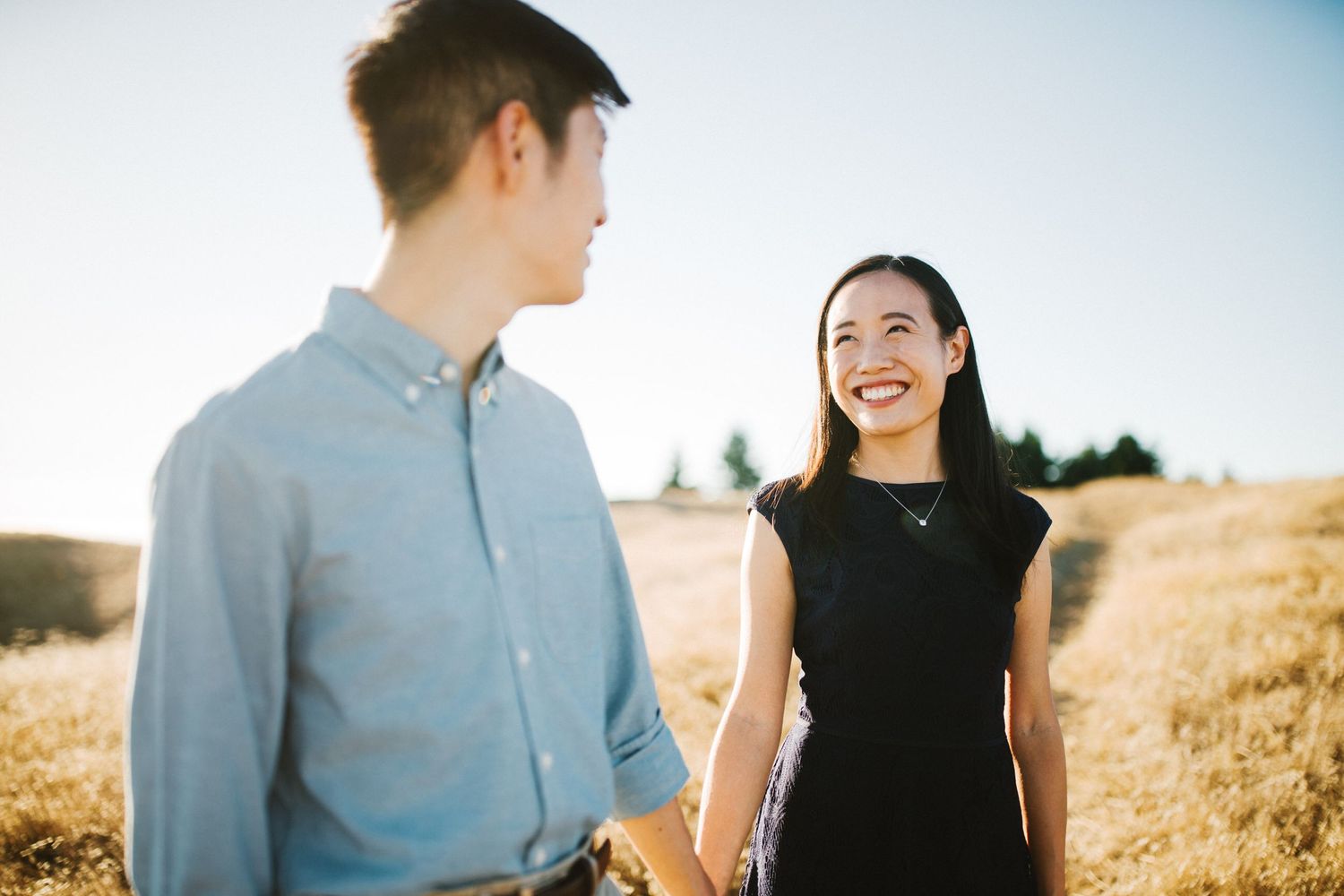 A couple shares a joyful moment together in a sunlit golden field.