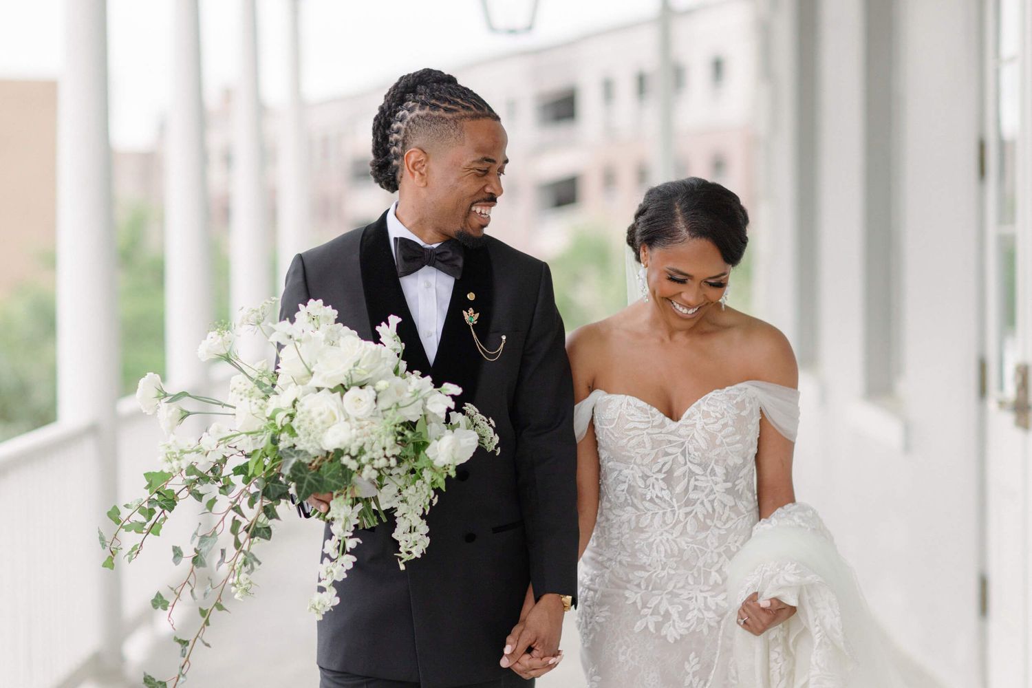 A wedding couple walking together with a stunning white cascading bouquet on their special day.