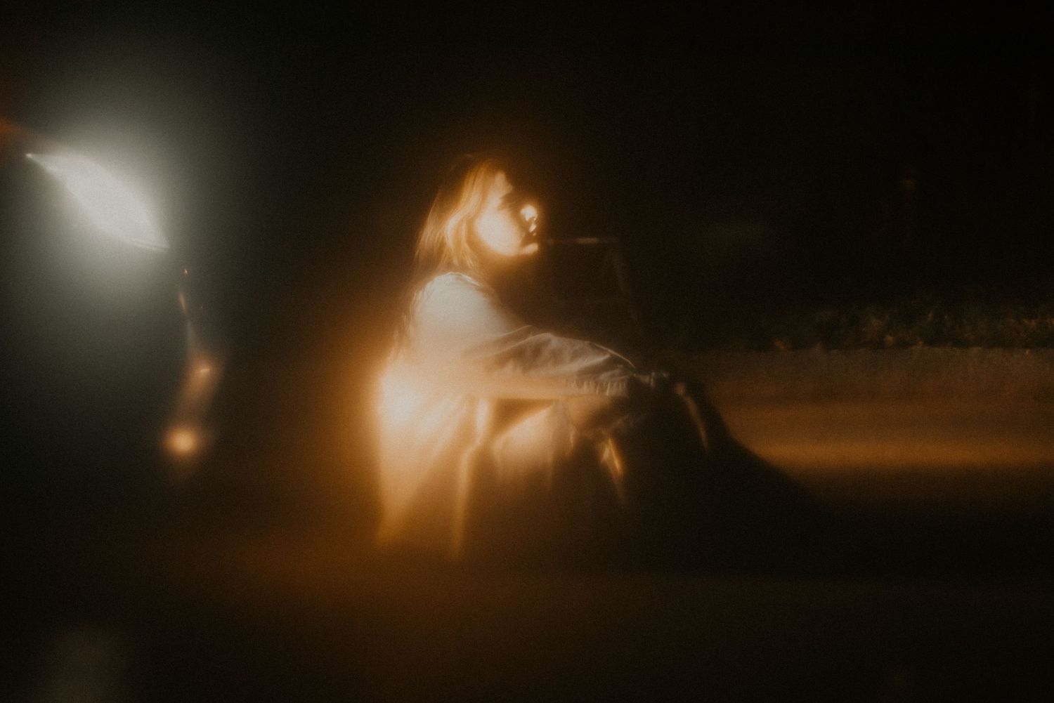 A moody nighttime portrait lit dramatically with warm glowing light.