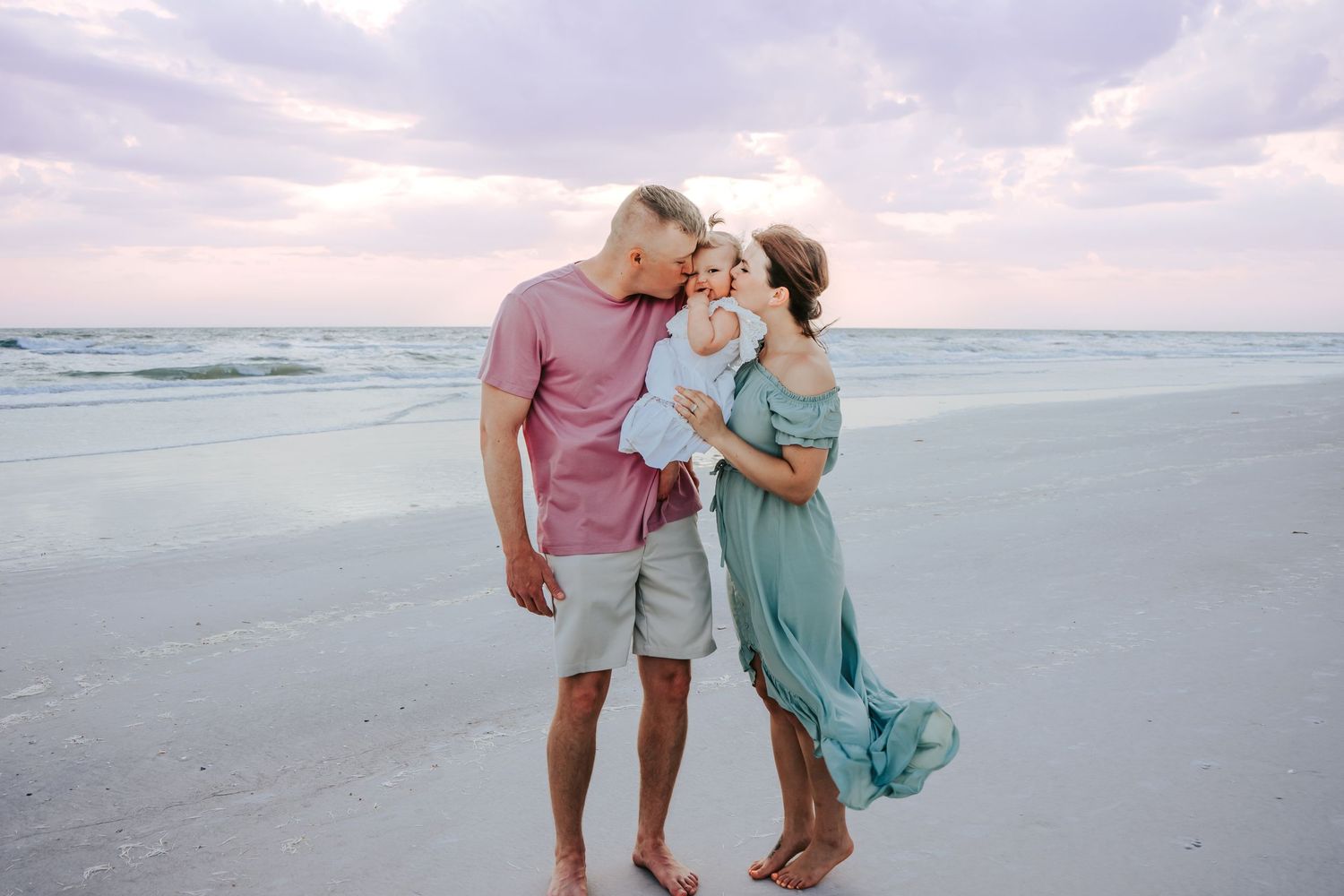 Outdoor Family Session at Indian Rocks Beach in Indian Rocks, FL; parents kissing babies cheeks on beach