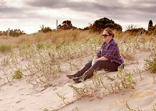 Artistic beach portrait shot with moody sky and sand dunes in the background.