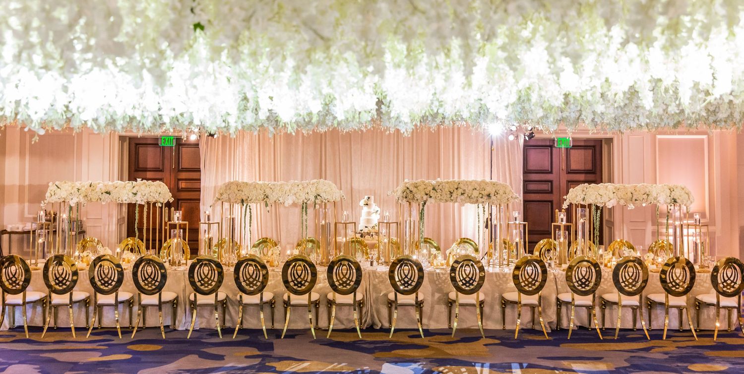 Panoramic view of an elegant ballroom with hanging floral installations and classic white decor.