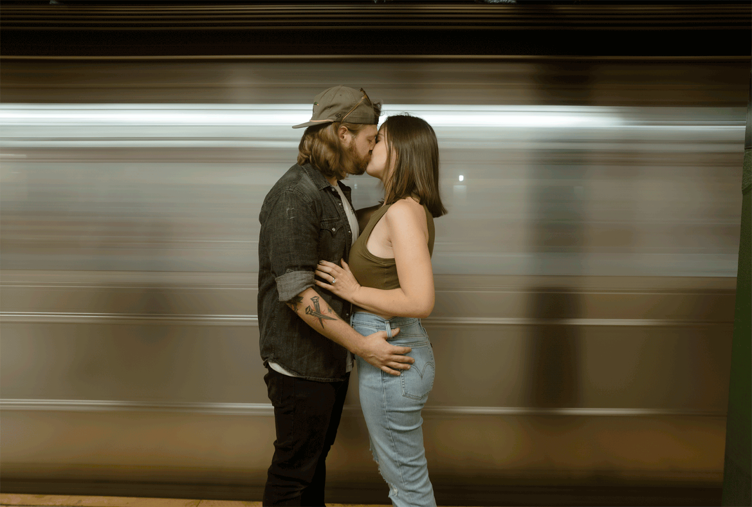 Romantic couple embracing in front of moving subway train with motion blur.