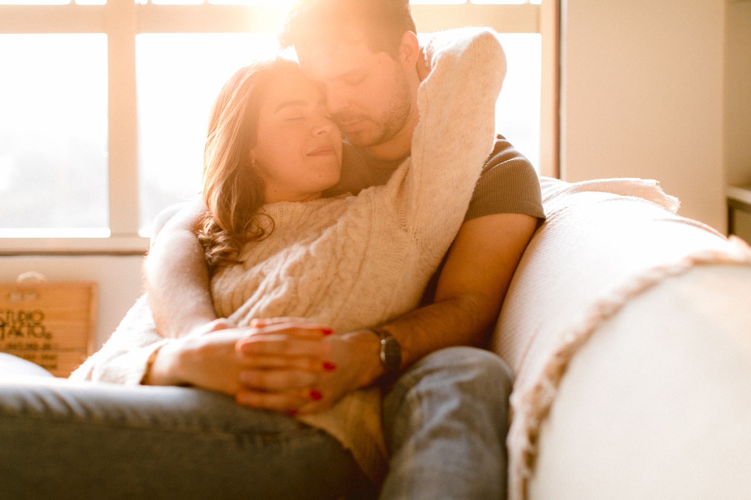 Intimate sunlit moment between couple relaxing on couch at home.