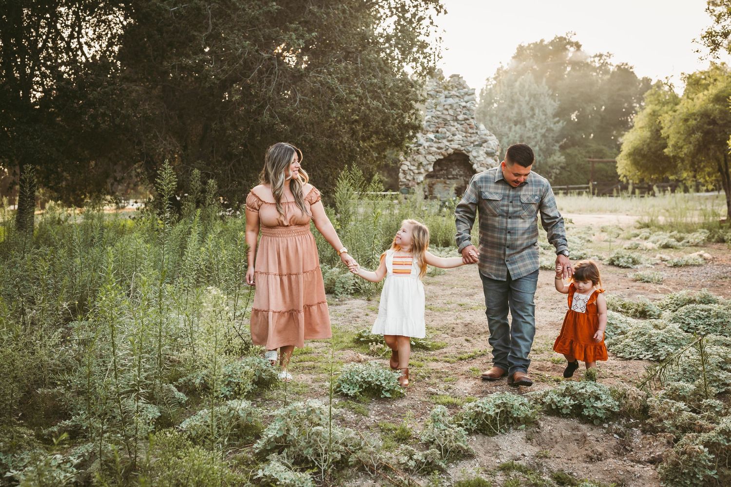 a family of four walking through green grass during their fall family photo session with heidi grace photography
