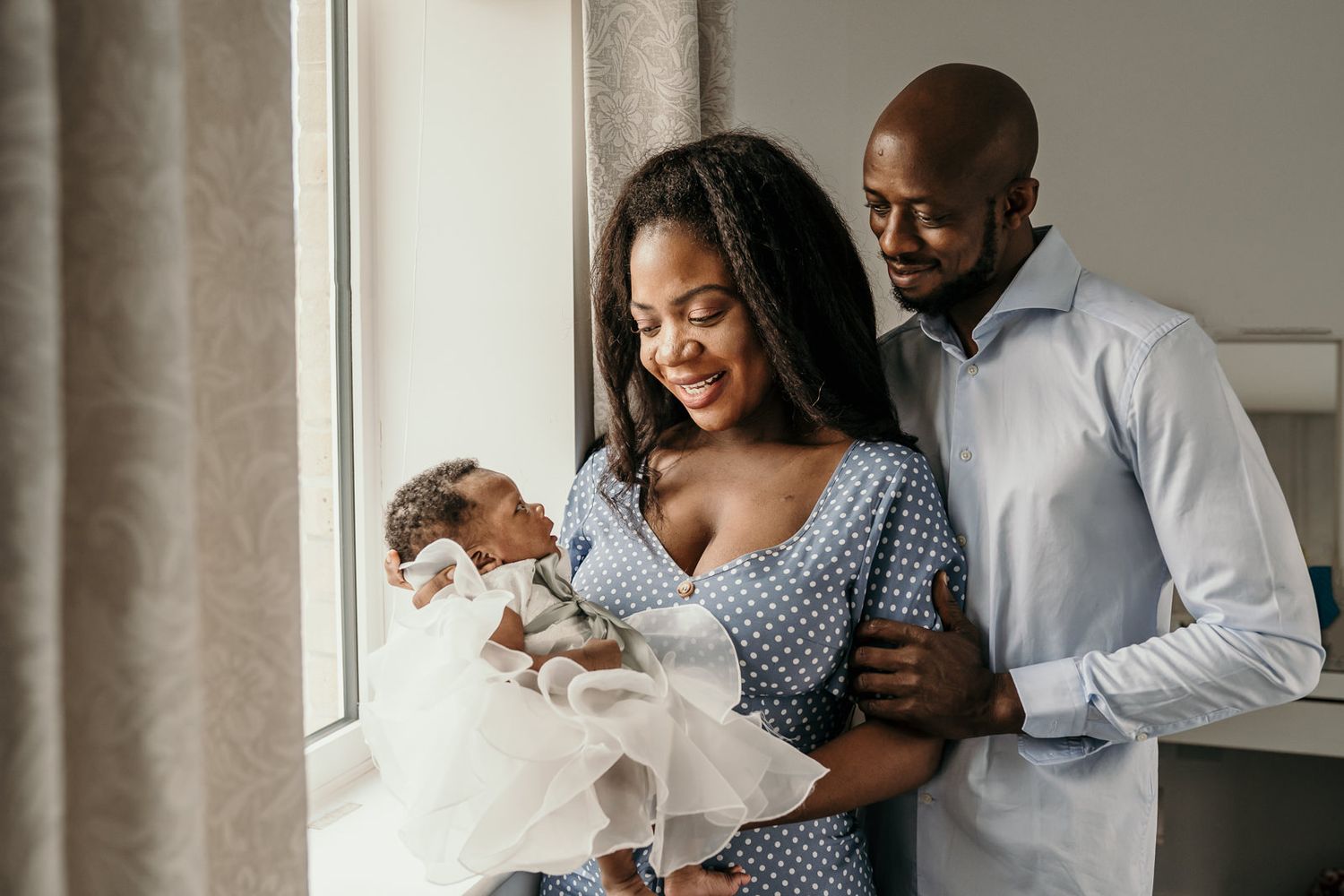 new parents holding their newborn baby and lovingly looking at her