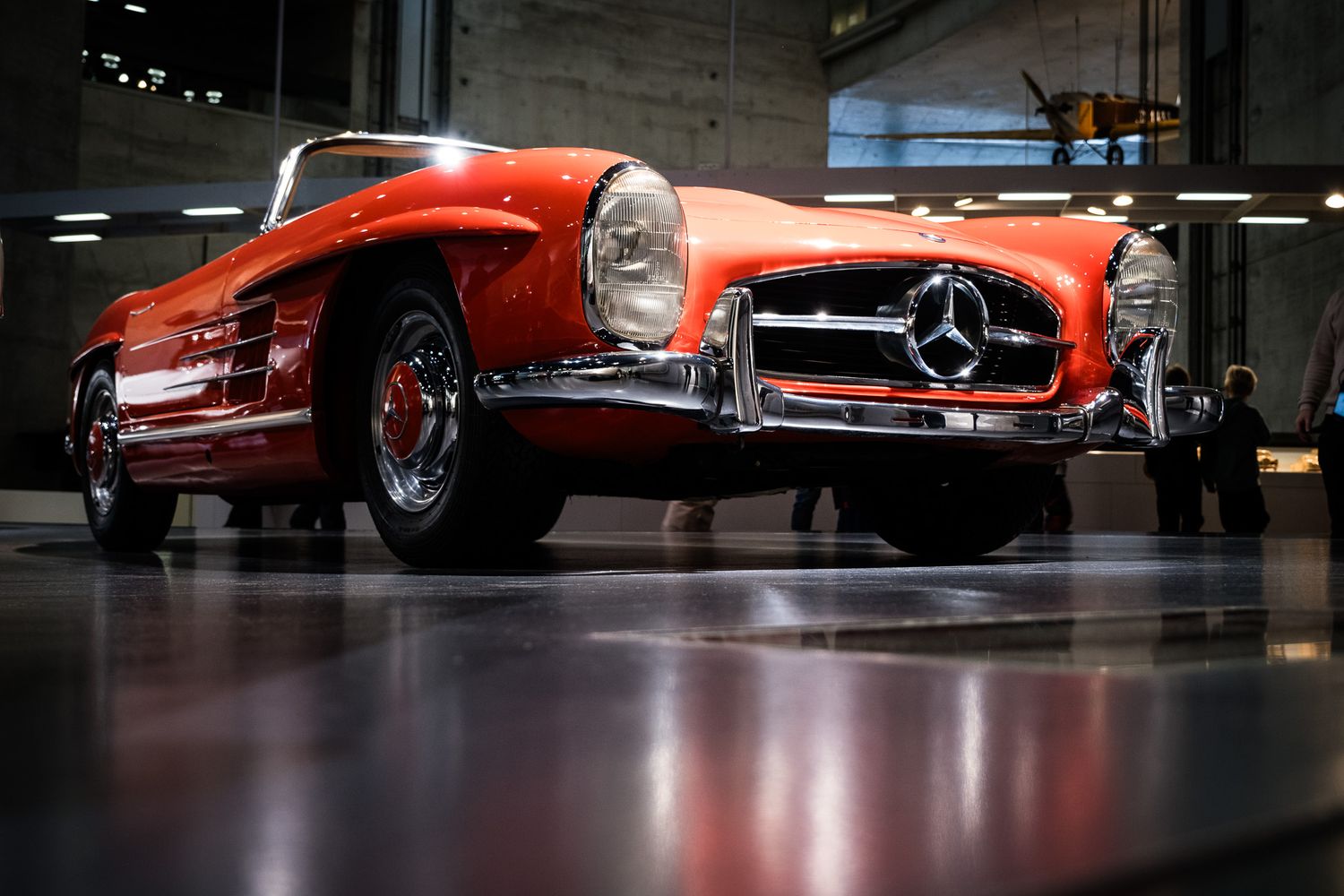 Classic red Mercedes-Benz 190SL vintage convertible sports car displayed in a museum showroom.