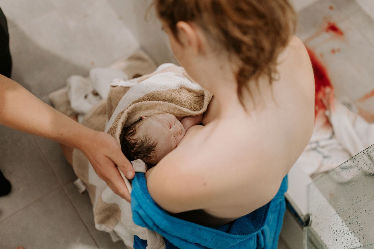 A newborn baby swaddled in white fabric sleeping on beige textiles.