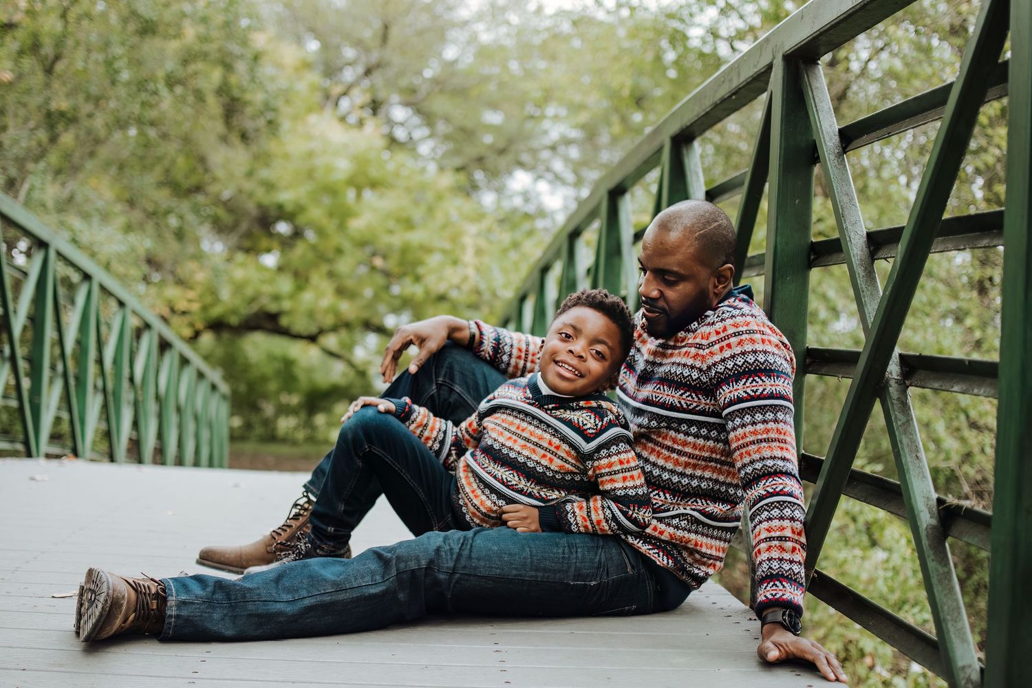 A sweet candid moment shared on a green bridge wearing matching patterned sweaters.