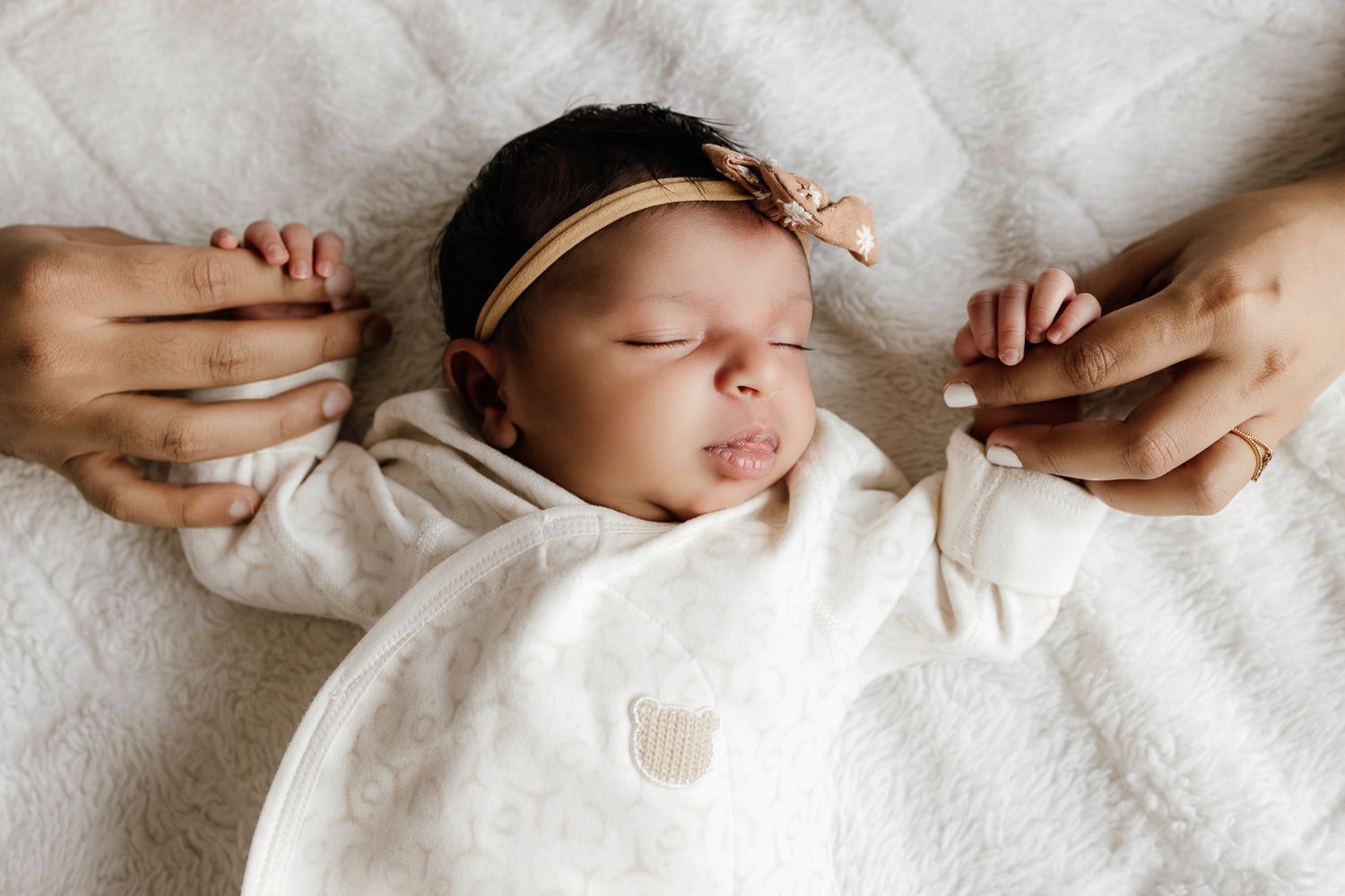 Baby holds parents fingers while sleeping at in-home newborn session