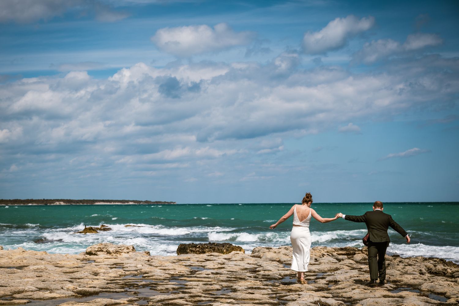 Bruidspaar hand in hand aan zee tijdens destination wedding, vastgelegd door Bart Boodts met focus op vrijheid, liefde en natuurlijke storyt