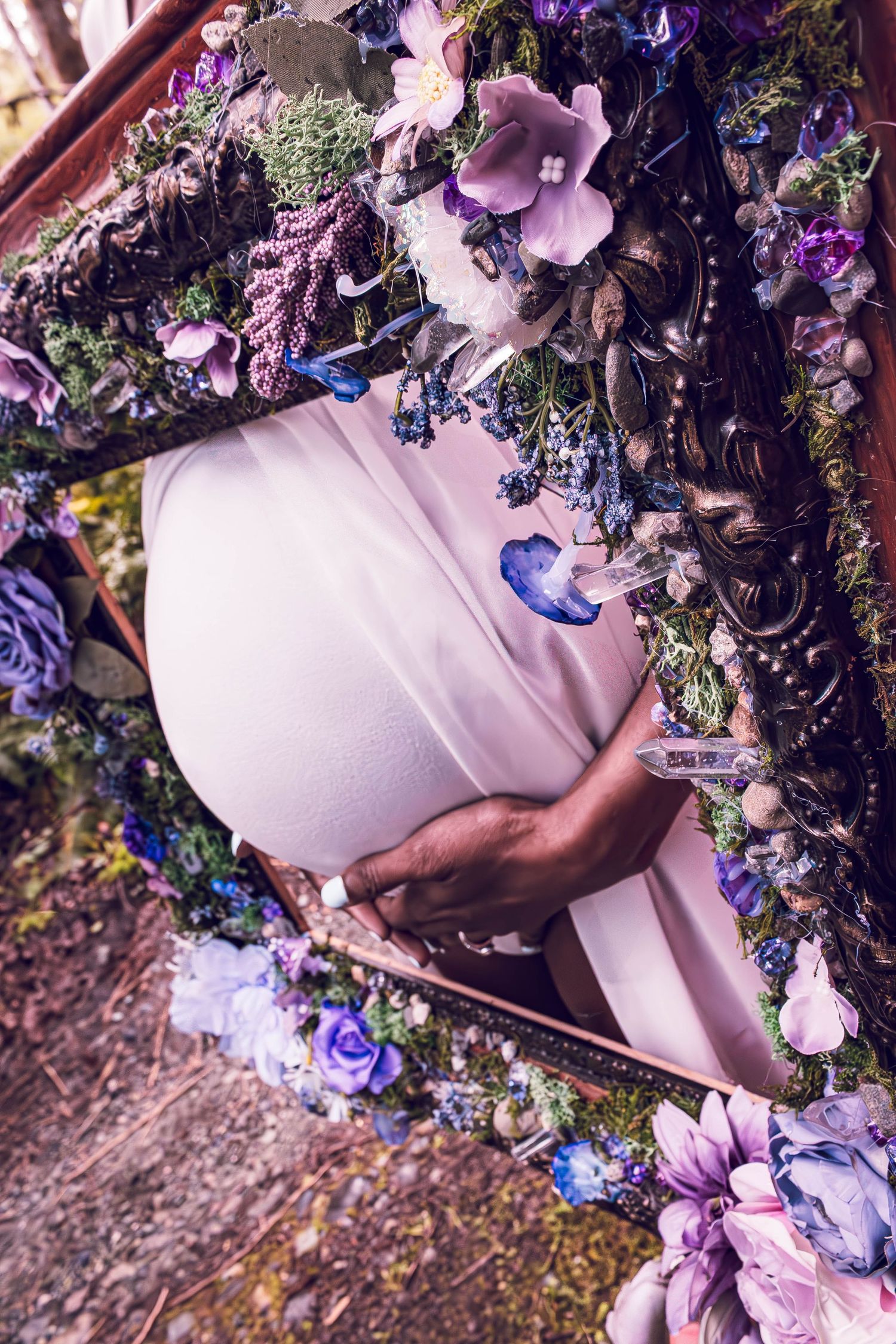 A gentle portrait through a floral frame of purple and blue blooms with butterflies and delicate lighting effects.