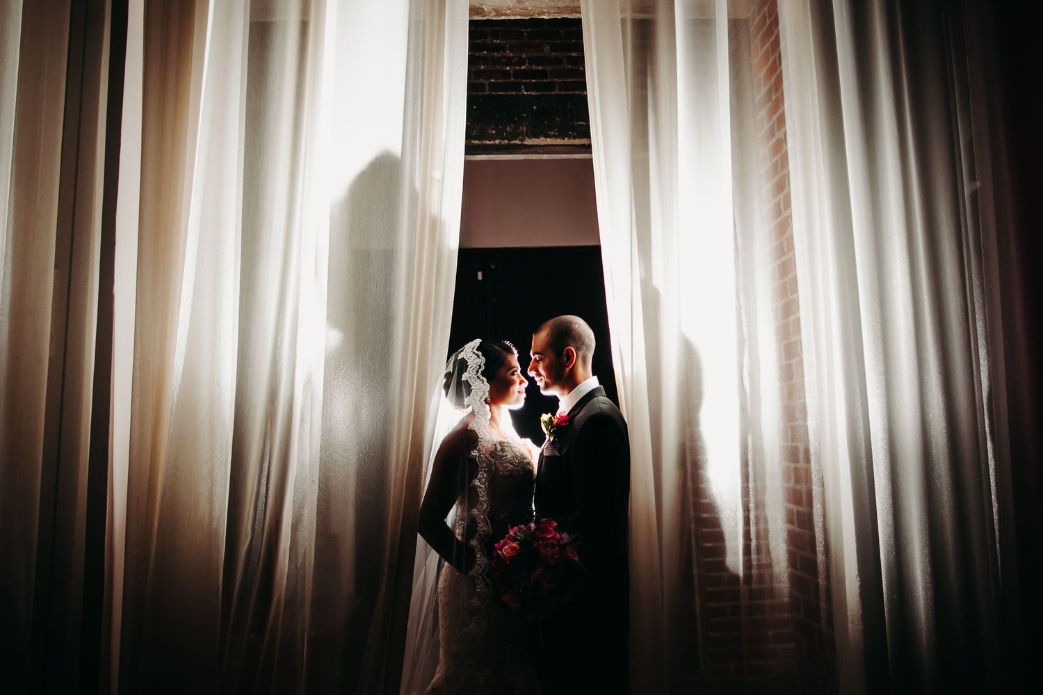 A series of four black and white photos showing a wedding couple's silhouettes against light curtains in an elegant setting.