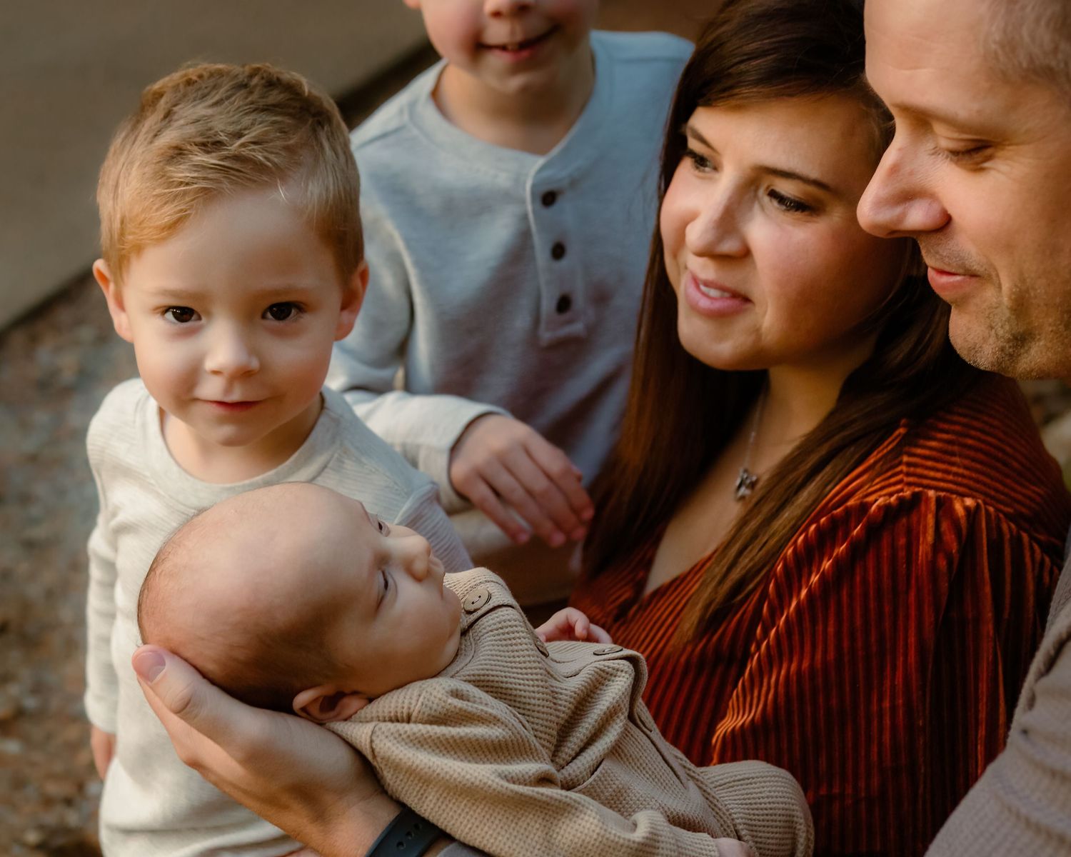 Intimate family moment with newborn baby and siblings gathered close together.