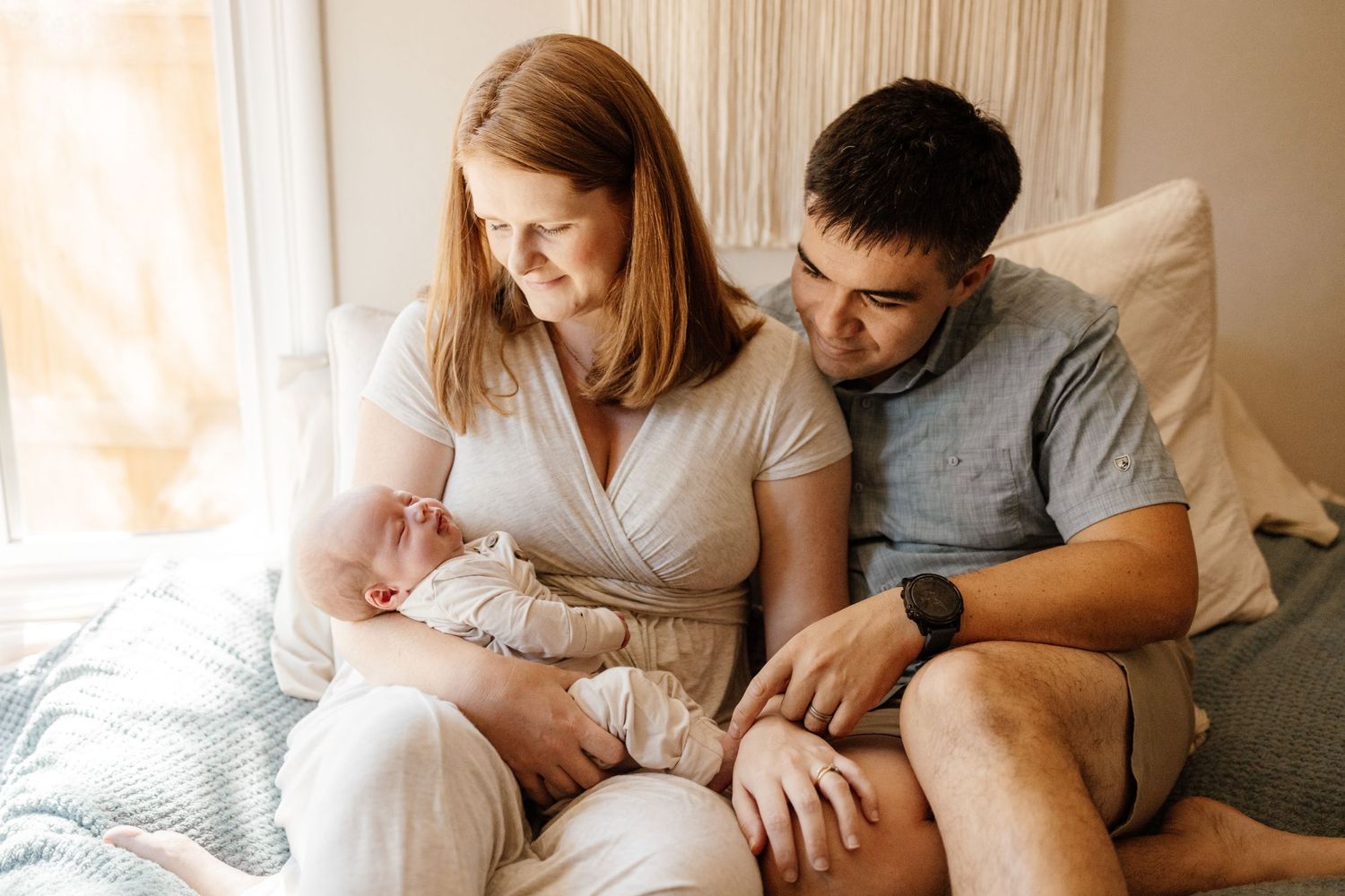 A mom and dad look lovingly at their sleeping baby during a newborn photo session