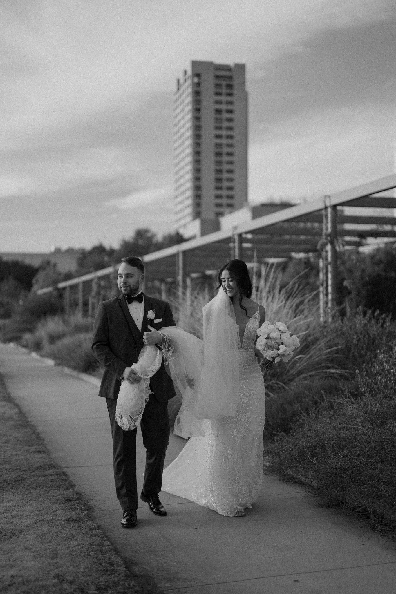 A black and white wedding portrait with a city skyline in the background.
