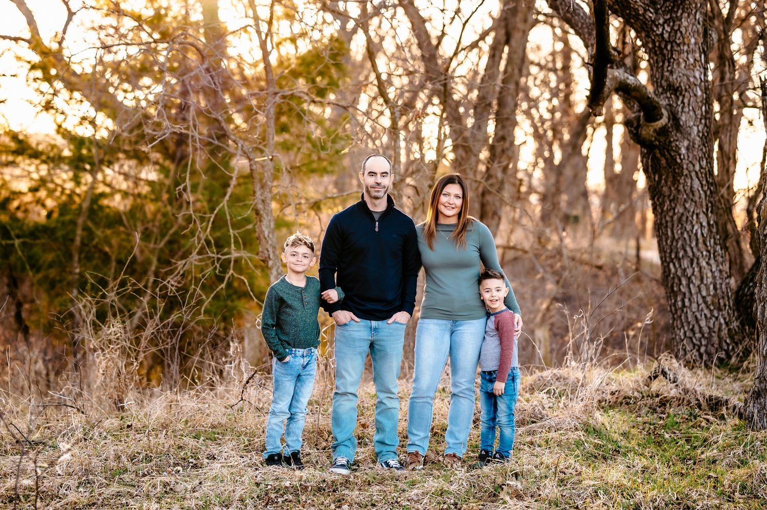 Family walking together on nature trail holding hands at sunset in autumn countryside.