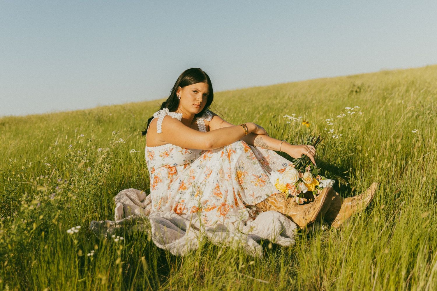 Woman in floral dress relaxing in a sunlit summer meadow.
