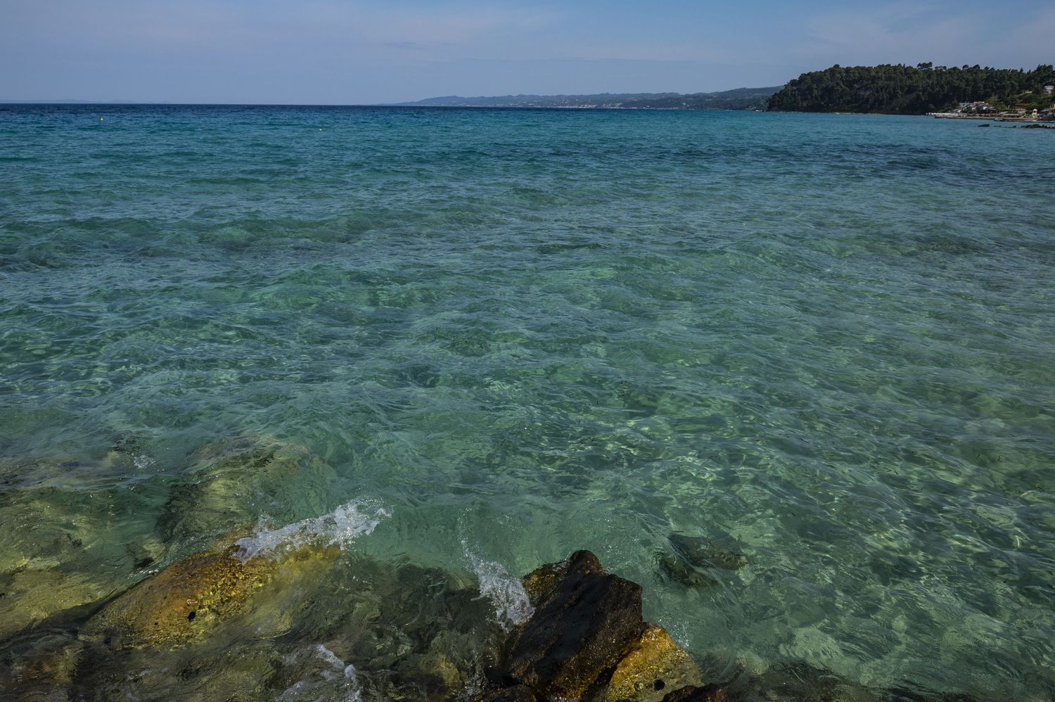 Crystal clear turquoise waters reveal a vibrant coral reef ecosystem beneath the surface in a tropical paradise.