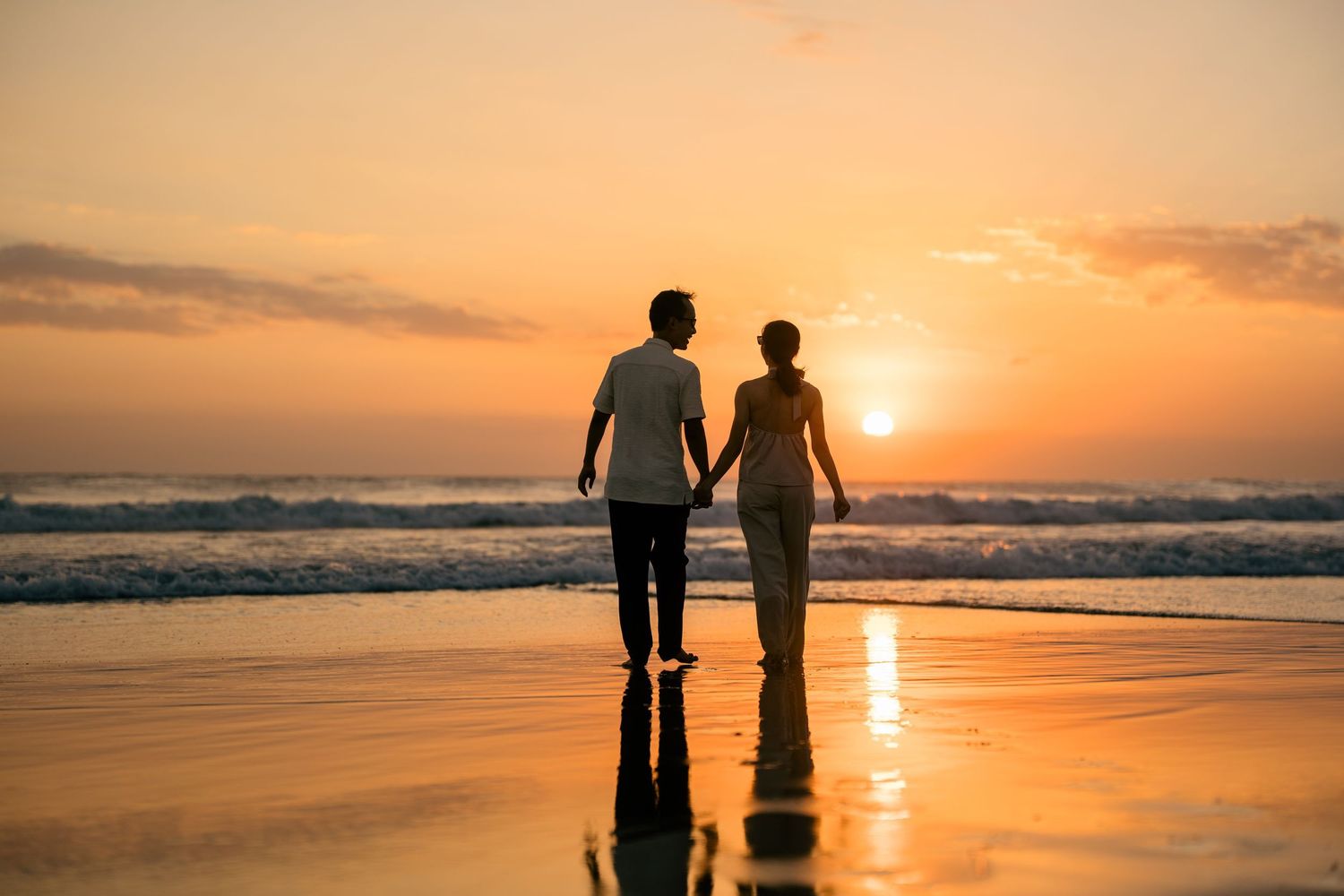 Couple walking along a green garden pathway surrounded by tropical plants.