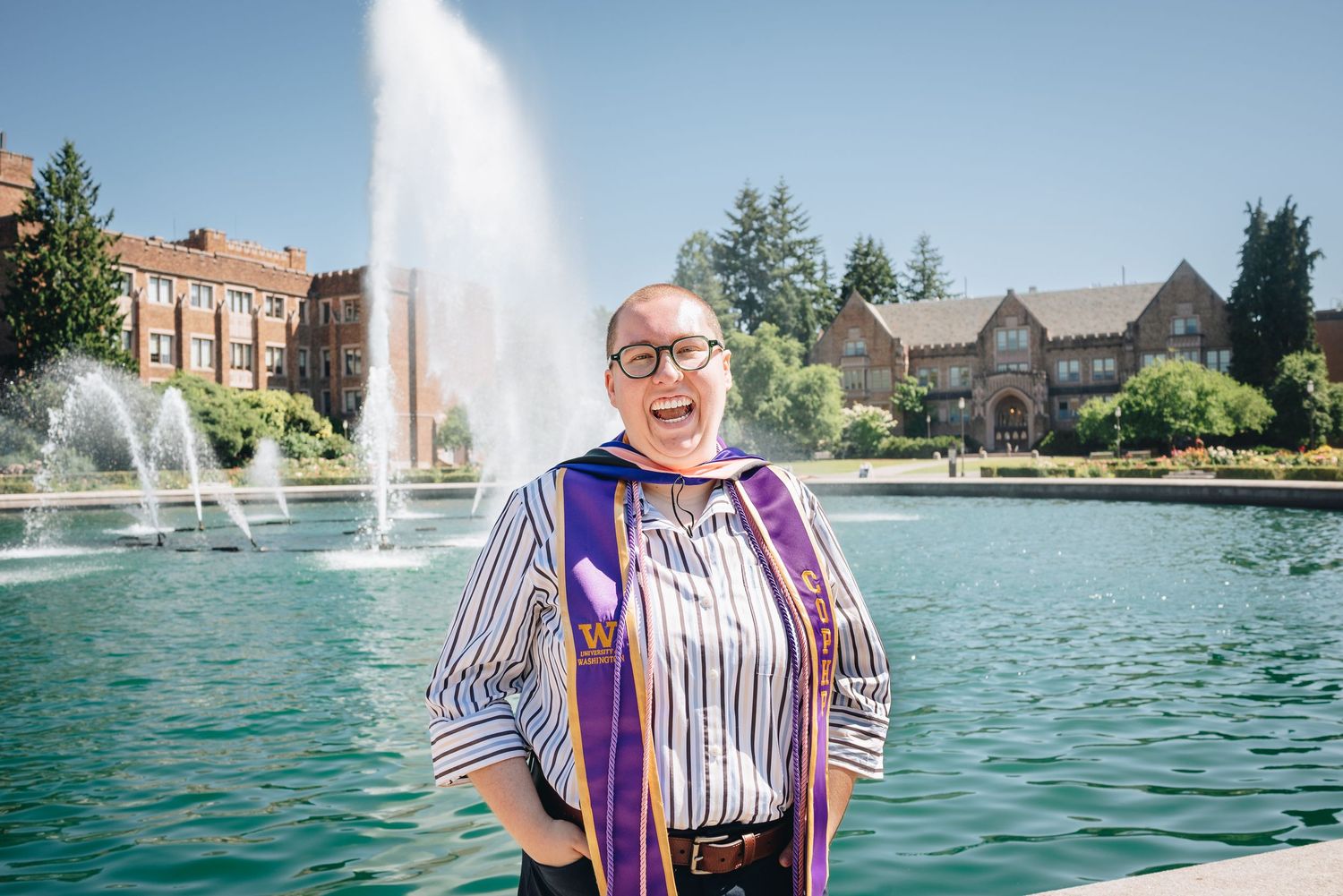 University of Washington graduate posing beside Drumheller Fountain during graduation photos in Seattle.