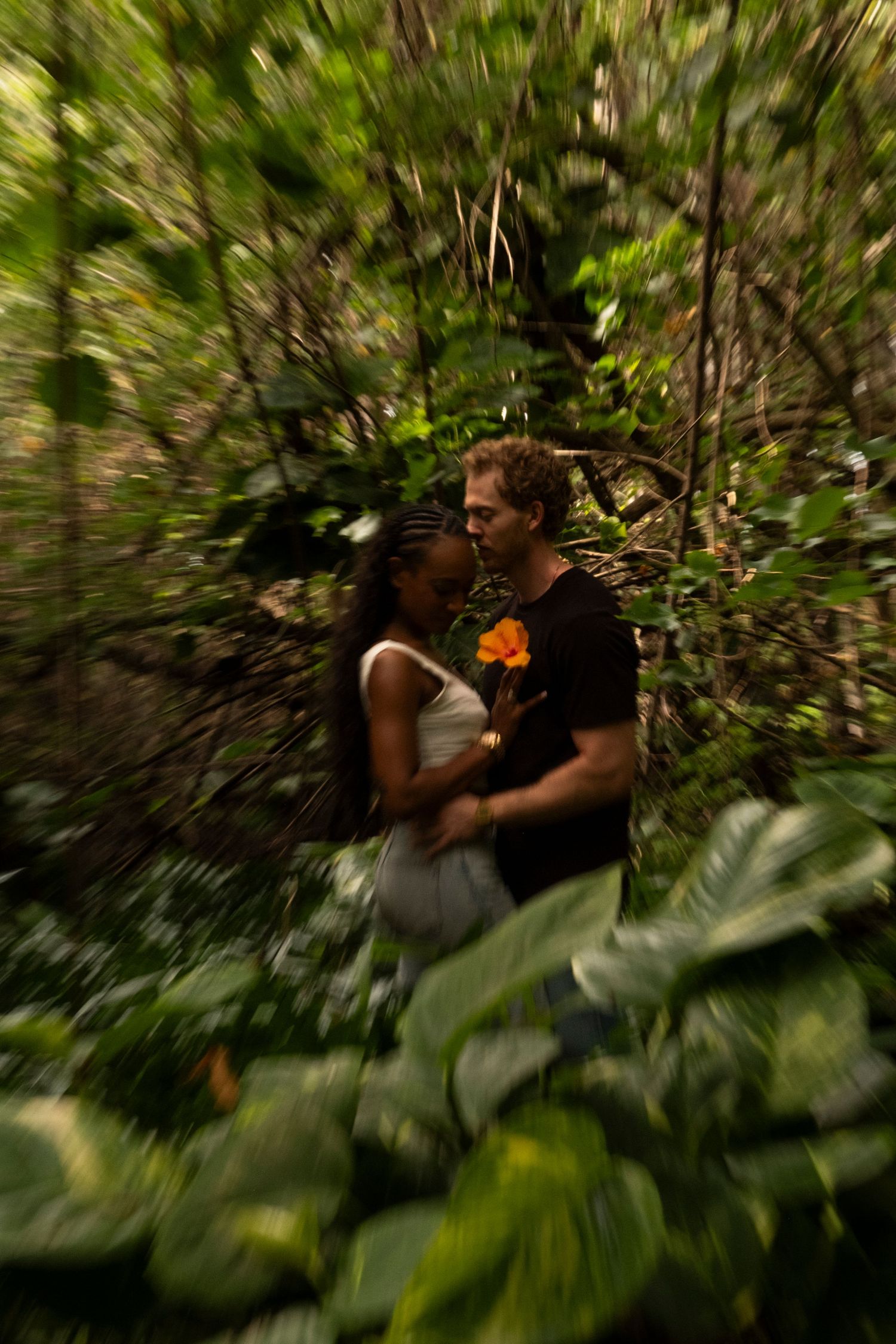 Couple embracing in a lush tropical forest during a North Shore Oahu couples photography session surrounded by vibrant greenery.
