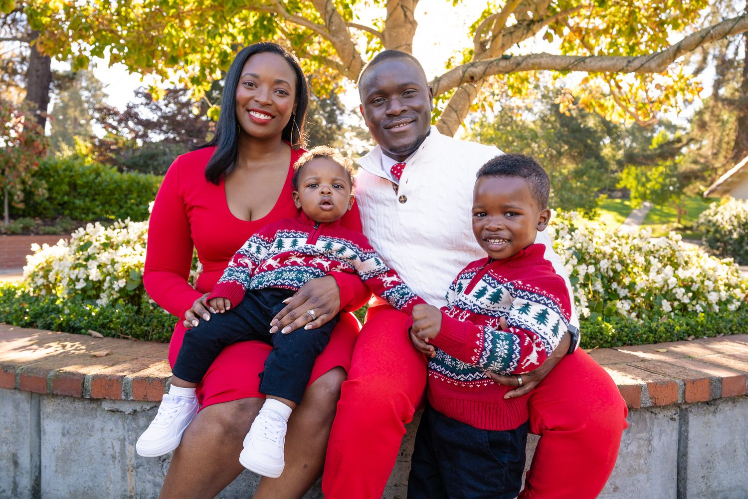 A joyful family of four in matching Christmas sweaters poses outdoors for a festive holiday portrait.