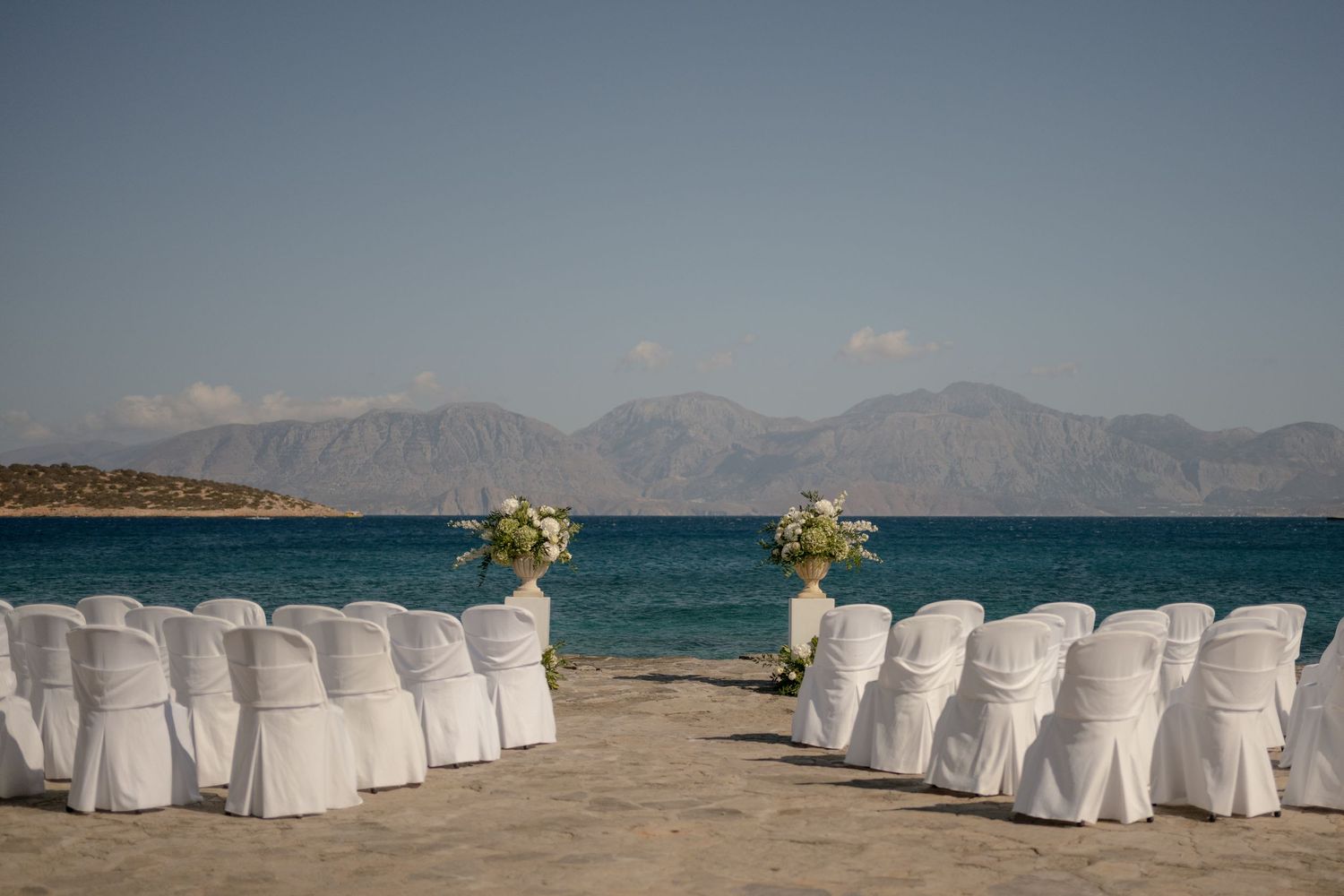 Panoramic view of a beachside restaurant at sunset with diners seated at tables overlooking the Mediterranean Sea.