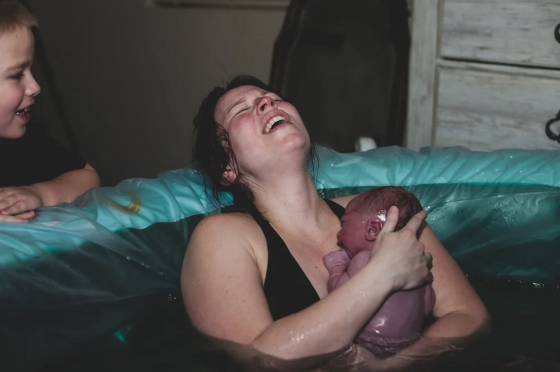 A tender moment shared in a birthing pool showing pure joy and raw emotion.