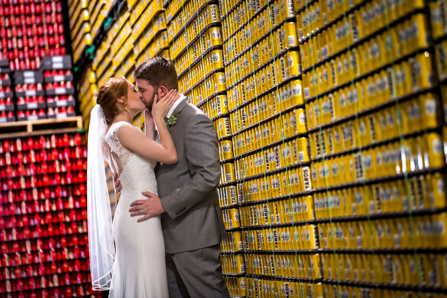 A couple shares a romantic kiss in front of a vibrant yellow and red wall display.