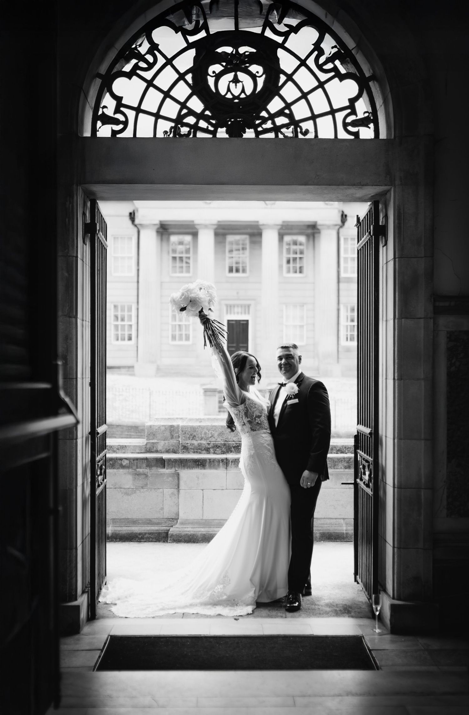 A romantic black and white wedding moment captured on a grand checkered floor staircase with ornate architectural details.