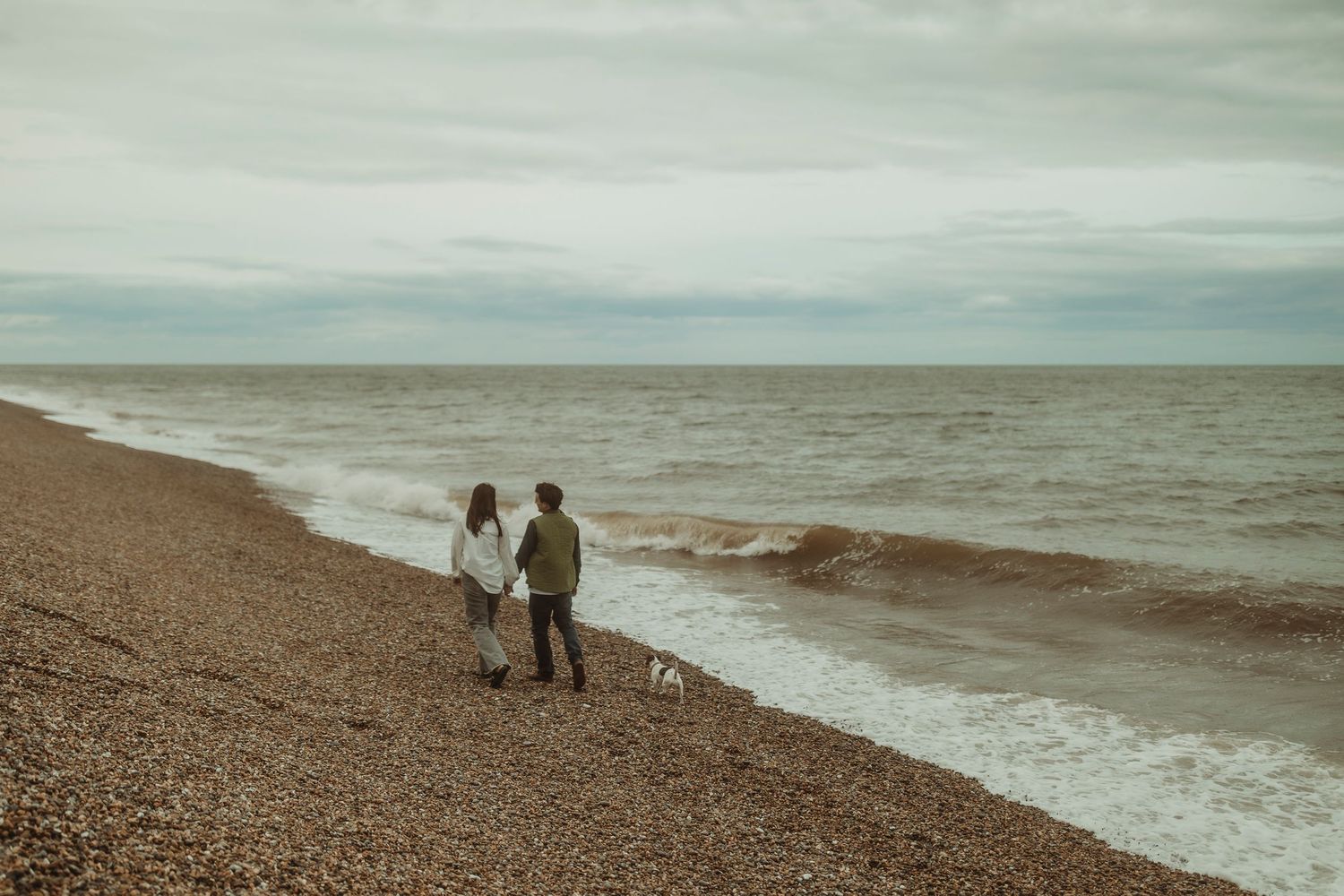 couple walk on Norfolk beach engagement photography