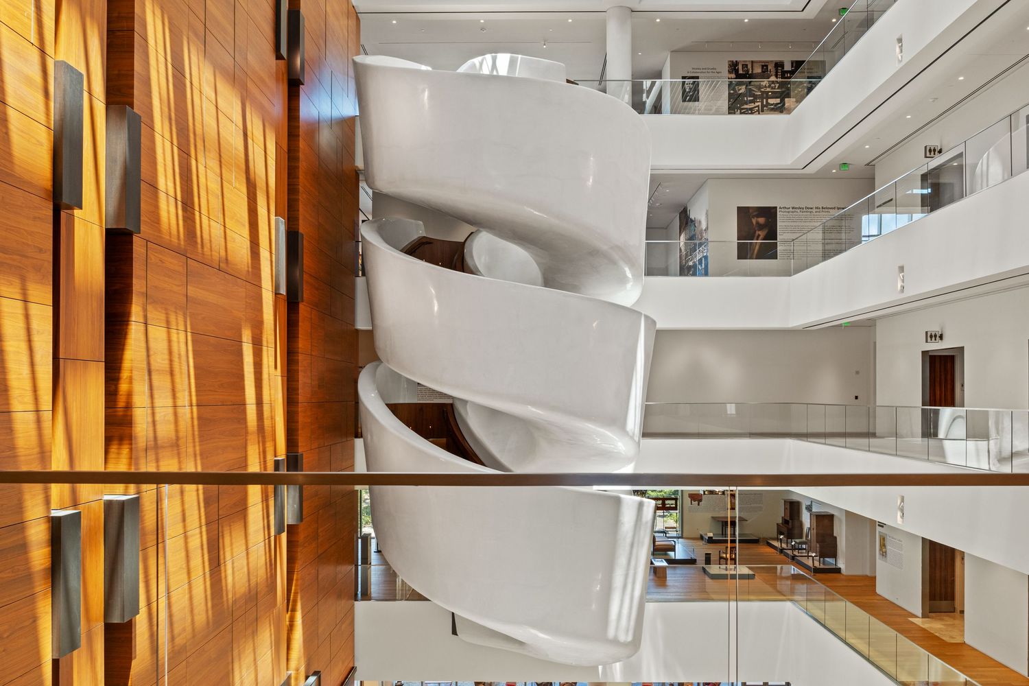 Modern office interior with curved white staircase and natural lighting.